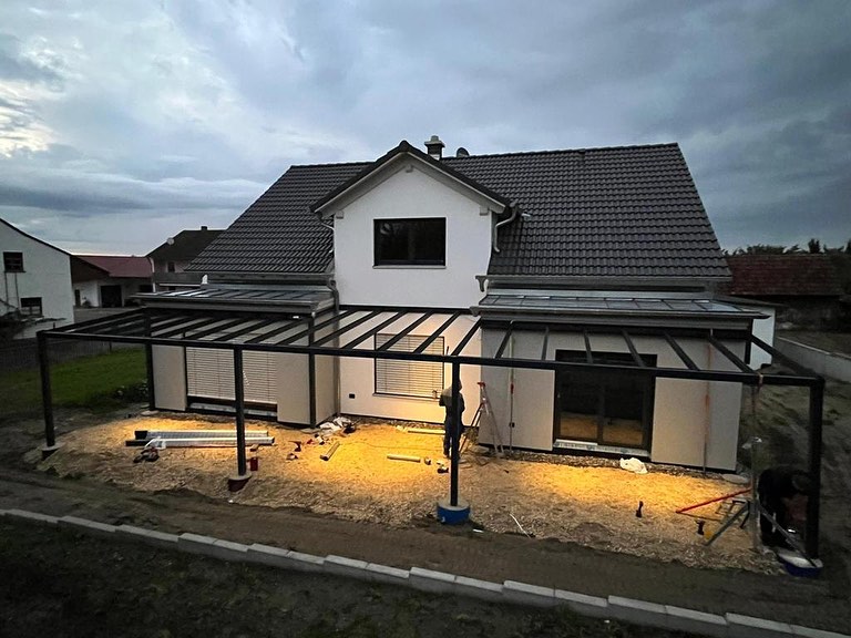 Montage einer Terrassenüberdachung an einem modernen Einfamilienhaus