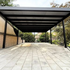 Ein Carport aus Aluminium in Regensburg in einem Garten mit großen grünen Bäumen