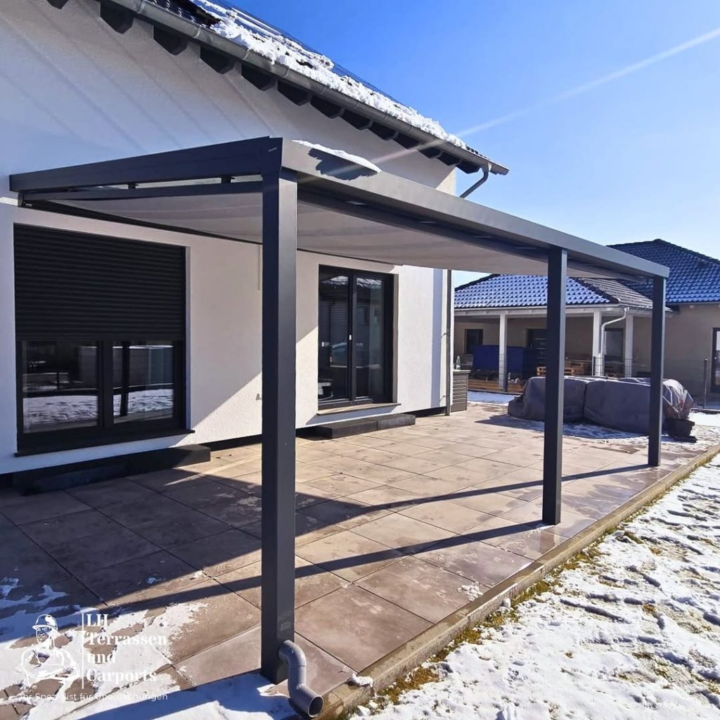 Eine Terrassenüberdachung aus Aluminium im Winter mit Schnee im Garten und auf dem Dach. Widerstandsfähigkeit einer Aluminiumkonstruktion und ihre Vorteile gegenüber anderen Materialien.